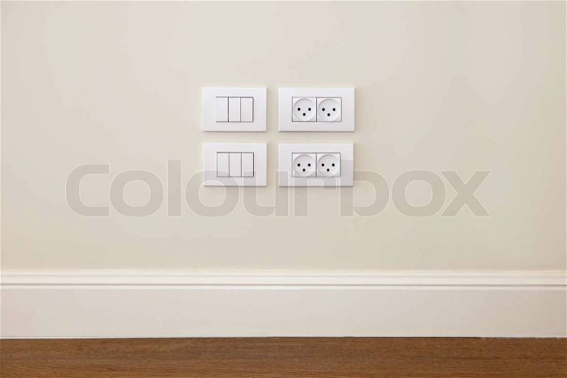 Empty wall with wooden floor. On the wall power outlet and light switch, stock photo