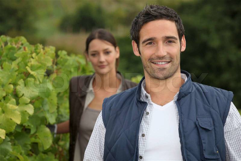 Young farmer stood with wife in vineyard, stock photo