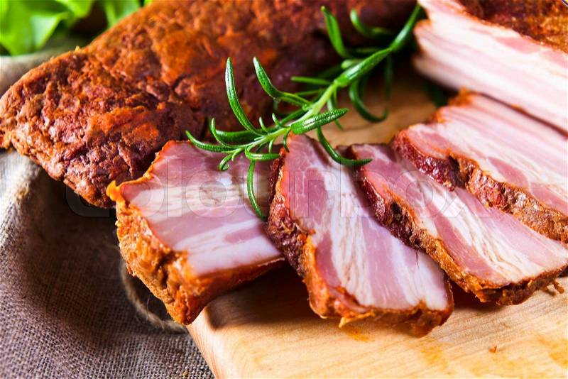 Smoked meat with rosemary on kitchen table, stock photo