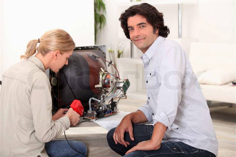 Couple repairing broken television, stock photo