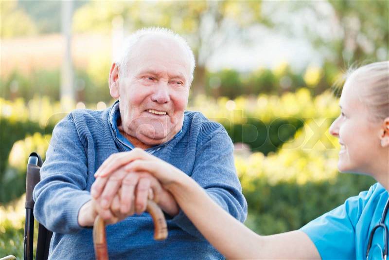 Young happy doctor giving support to his elderly patient, stock photo