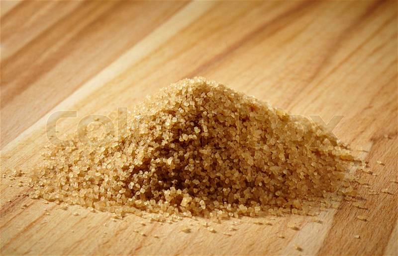 Brown sugar heap on wooden table, stock photo