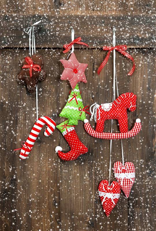 Christmas decoration handmade toys hanging over rustic wooden background. nostalgic retro style picture with falling snow effect, stock photo