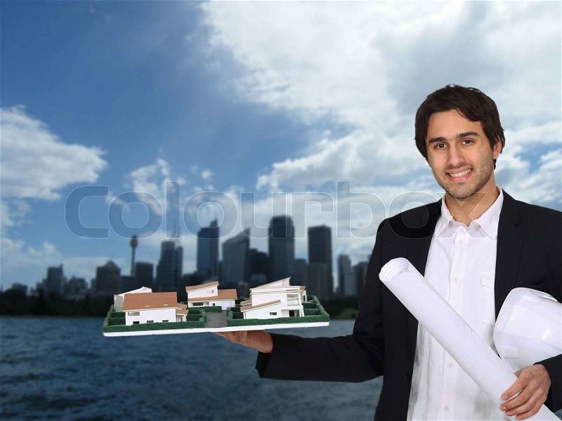Architect holding model with urban landscape in background, stock photo
