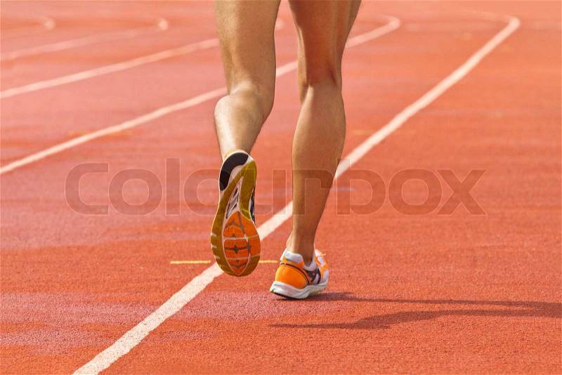 Male running at a track and field stadium, stock photo