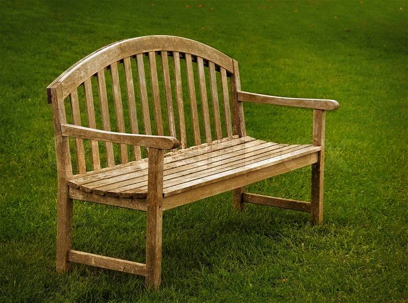 A wooden park bench with green grass, stock photo