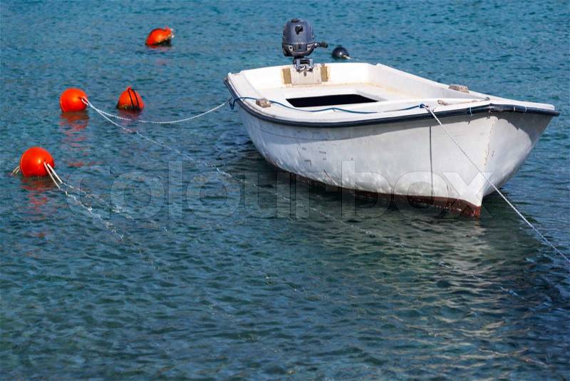 White wooden fishing boat floats moored in Adriatic sea water, Montenegro, stock photo