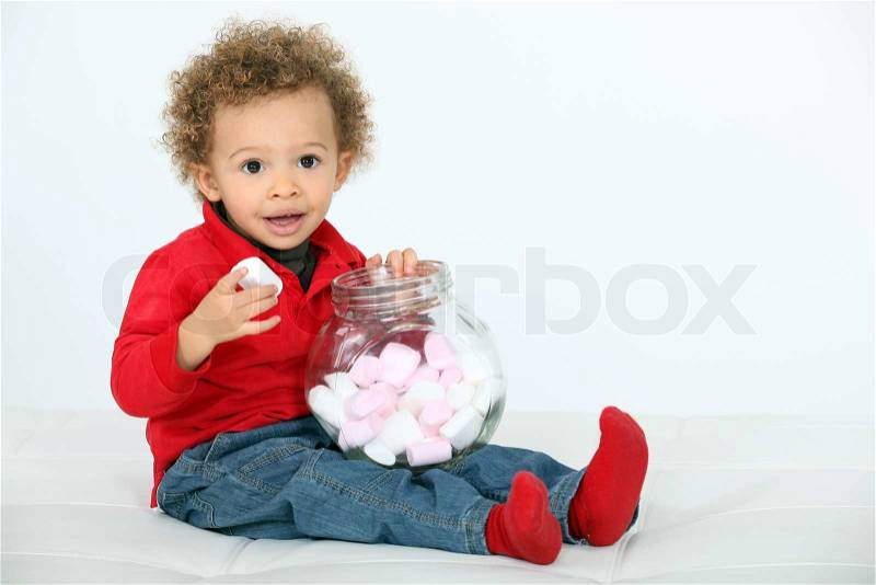 Cute little boy eating marshmallows, studio shot, stock photo