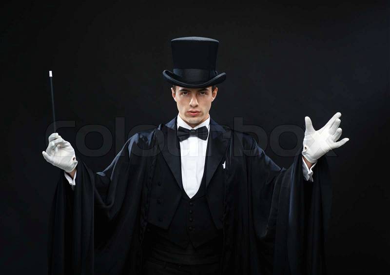 Performance, circus, show concept - magician in top hat with magic wand showing trick, stock photo