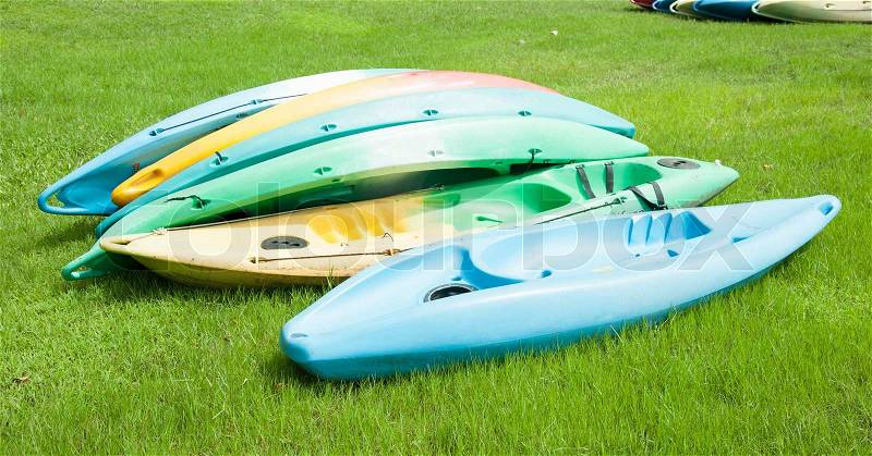 Colorful Kayaks Resting on Bright Green Grass, stock photo