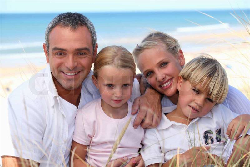 Two parents and their two children in front of the sea, stock photo