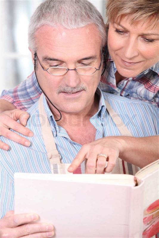Couple consulting cookbook, stock photo