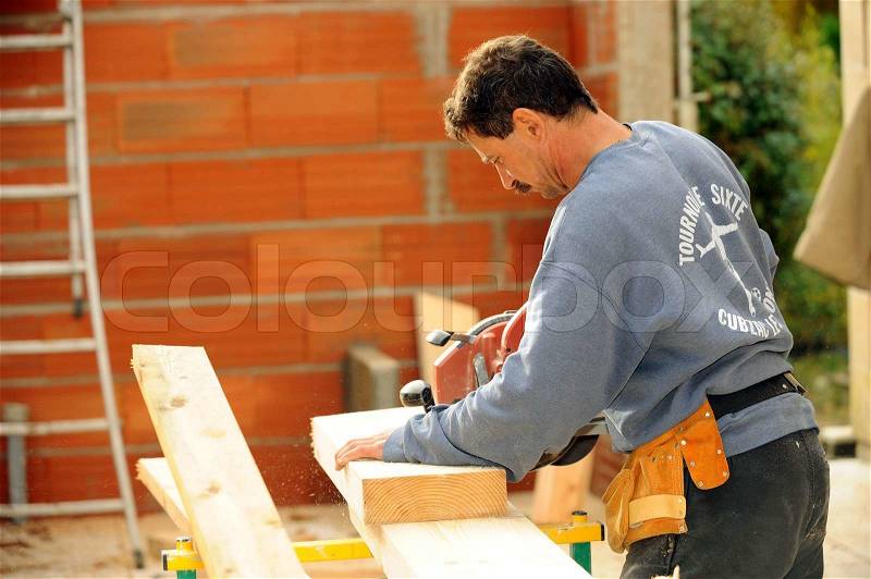 Manual worker using circular saw on site, stock photo