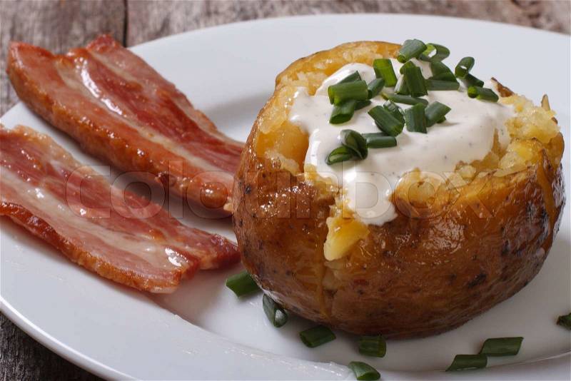 Baked potato filled with sour cream and slices of fried bacon, stock photo