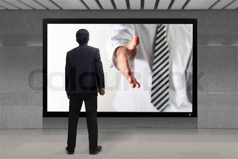 Business man gives a handshake out of TV screen, stock photo