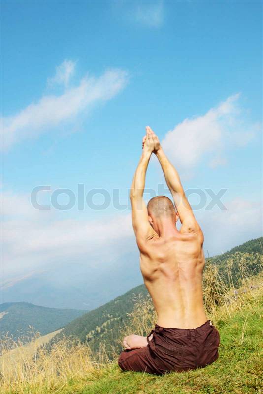 Young man is occupied yogi on the mountain, stock photo