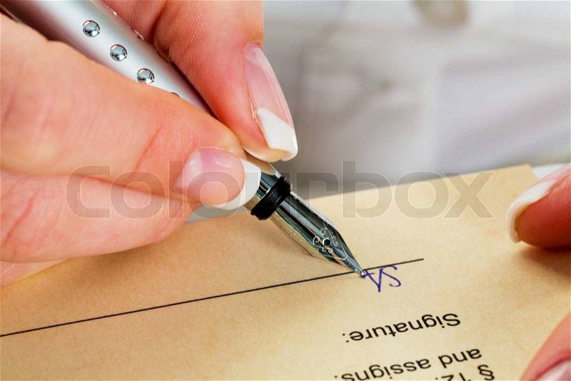 A woman signs a contract or a will with a fountain pen, stock photo