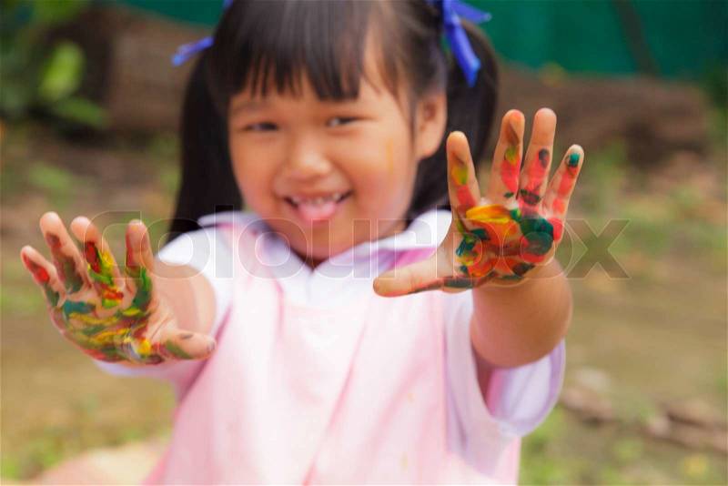 Little girl with hands painted in colorful paint , stock photo