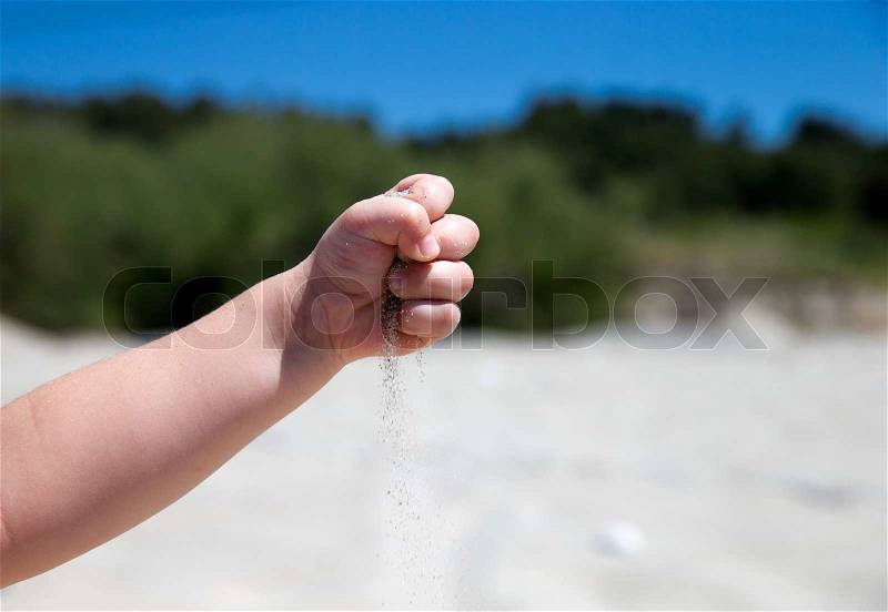 Hand throws sand on the seashore, stock photo