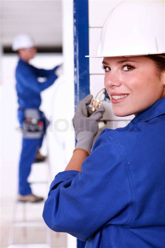Female electrician installing a power point, stock photo