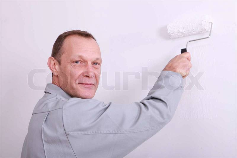 Man painting an interior wall white, stock photo