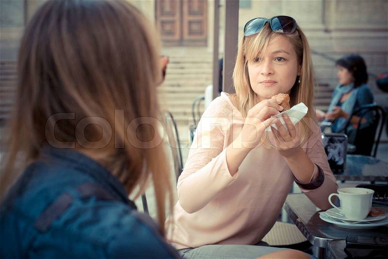 Two beautiful blonde women talking at the bar in the city, stock photo