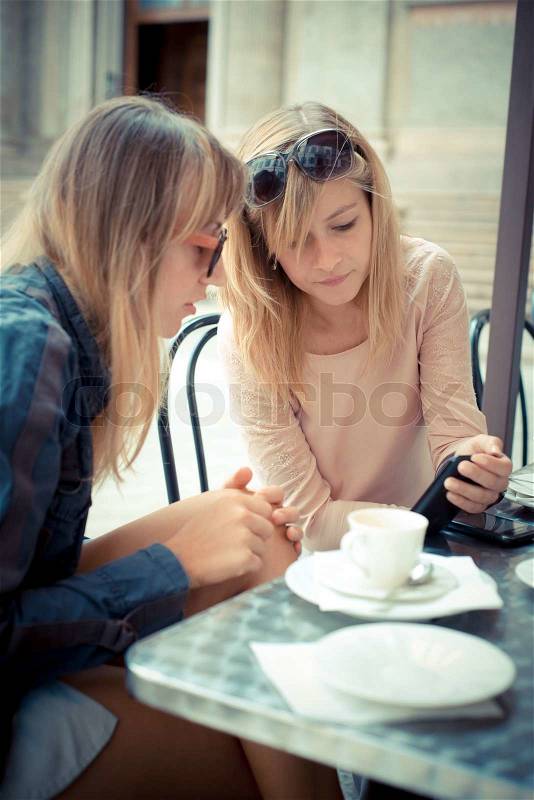Two beautiful blonde women talking at the bar, stock photo