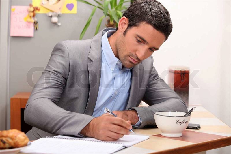 Businessman working at his breakfast bar, stock photo