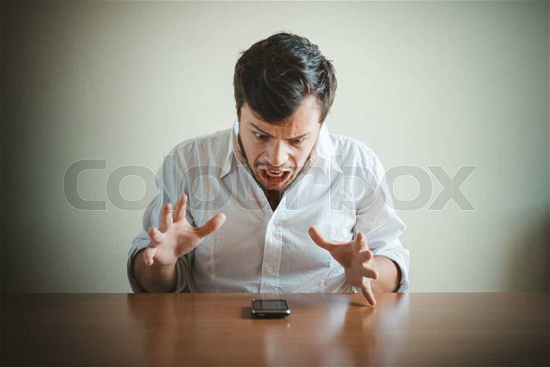 Young stylish man with white shirt on the phone behind a table, stock photo
