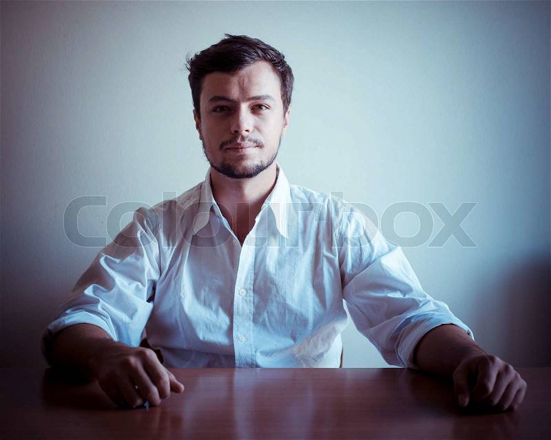 Young stylish man with white shirt behind a table, stock photo
