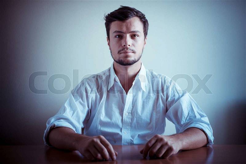 Young stylish man with white shirt behind a table, stock photo