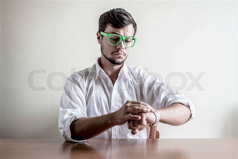 Young stylish man with white shirt time wristwatch behind a table, stock photo