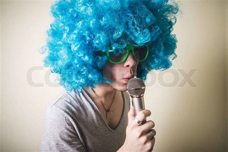 Funny guy with blue wig singing on white background, stock photo