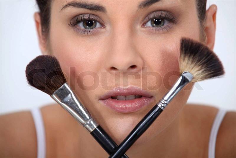 Closeup of a woman with makeup brushes, stock photo