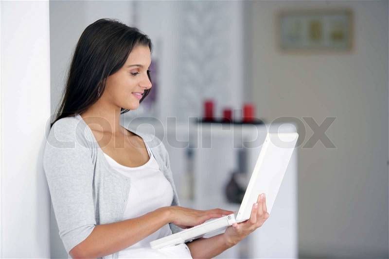 Woman using her laptop while standing up, stock photo