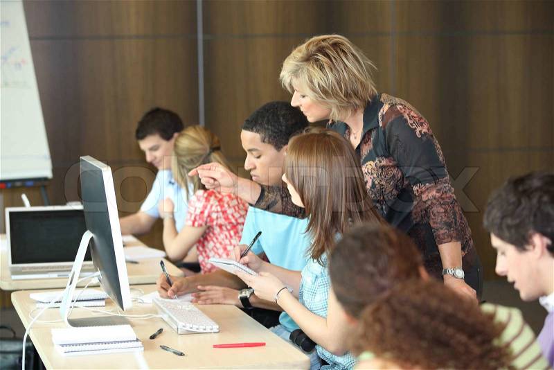 Group of students looking at a computer with a teacher, stock photo