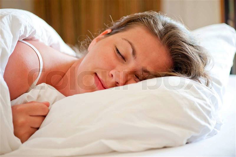 Woman sleeps on a snow-white bed in the morning, stock photo