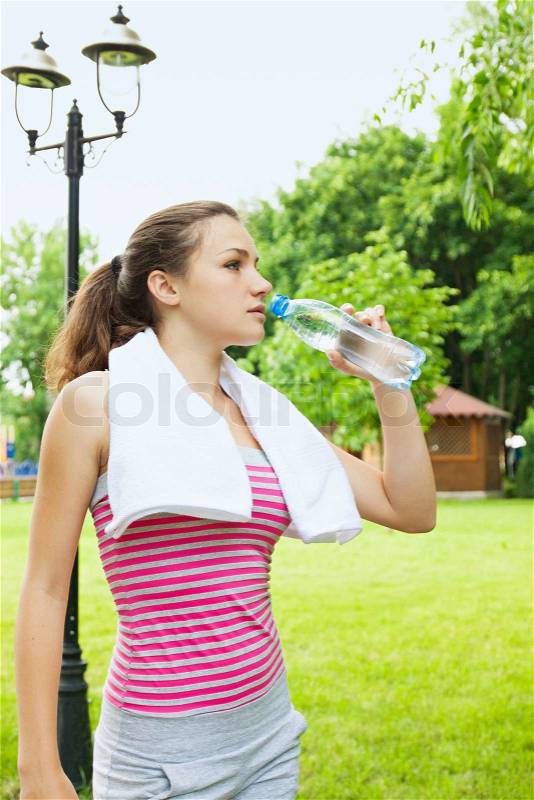A woman drinks water from a bottle, stock photo