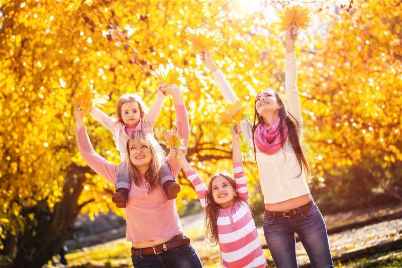 Family of four people playing in autumn park, stock photo