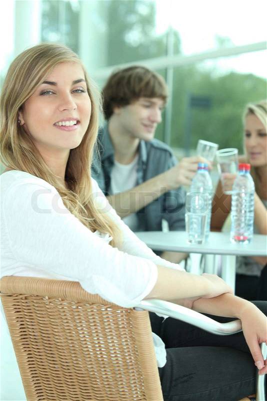 Three young people drinking water in a cafeteria, stock photo
