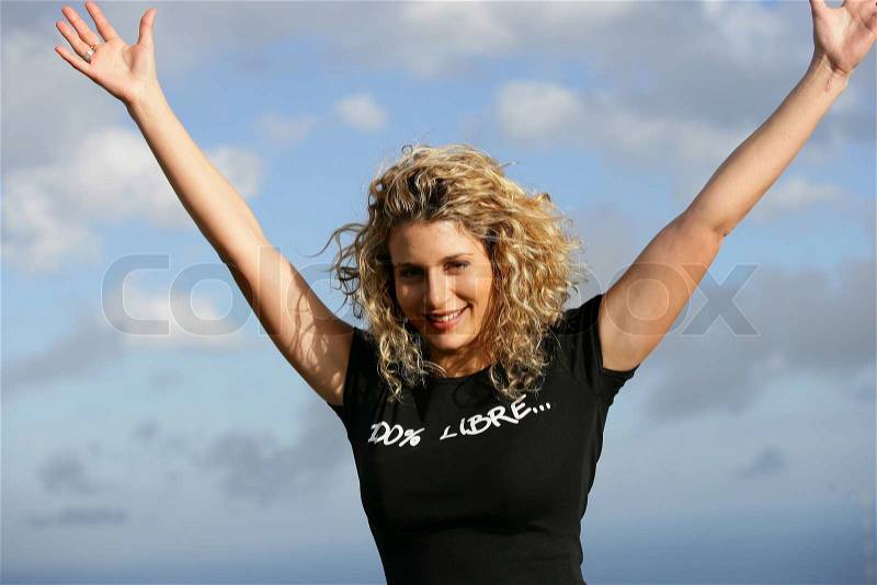Young woman with arms up outdoors, stock photo