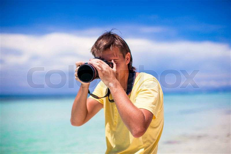 Close-up of a man with a camera on a white sand beach, stock photo