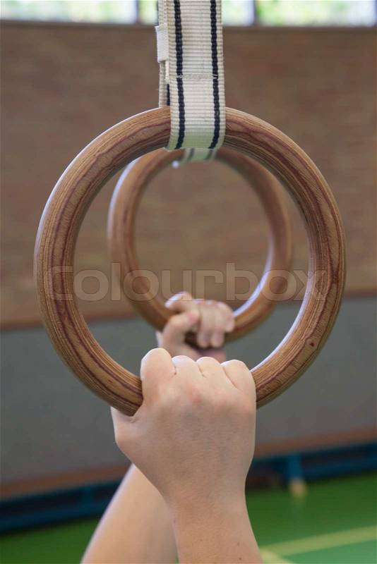 Human hanging in gymnastic rings, old school gym, stock photo