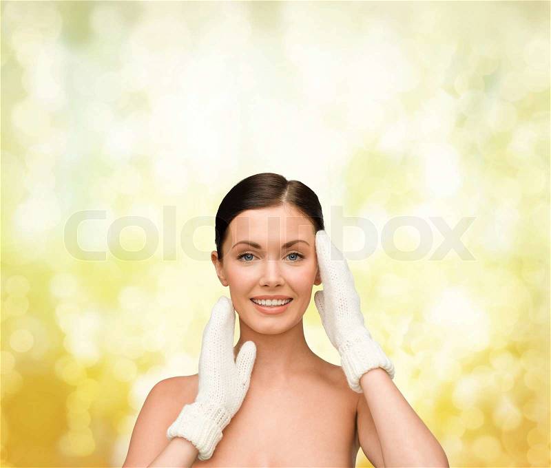 Beauty, winter, spa and health concept - smiling young woman in white mittens, stock photo