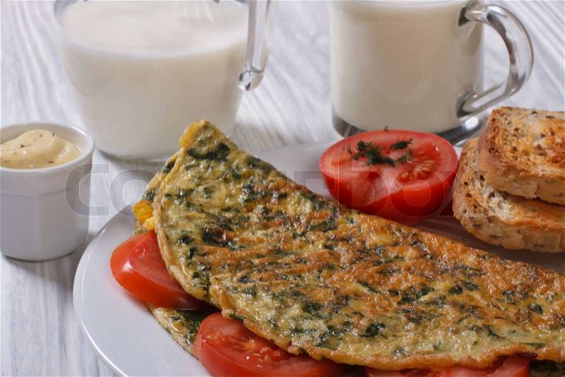 An omelet with spinach and tomatoes. Toast and milk, stock photo