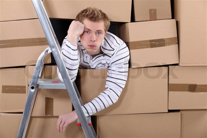Man stuck behind stacks of cardboard boxes, stock photo