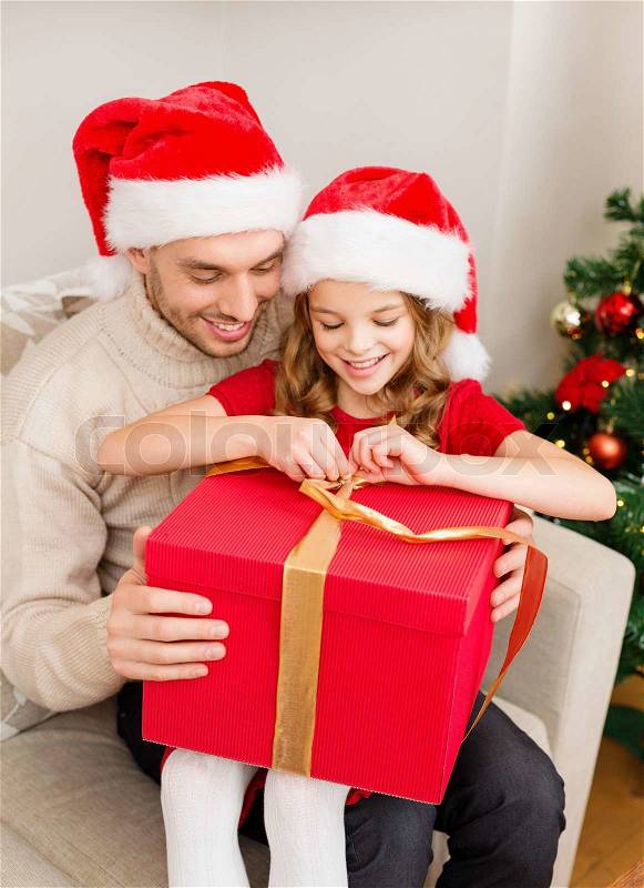 Family, christmas, x-mas, winter, happiness and people concept - smiling father and daughter in santa helper hats opening gift box, stock photo