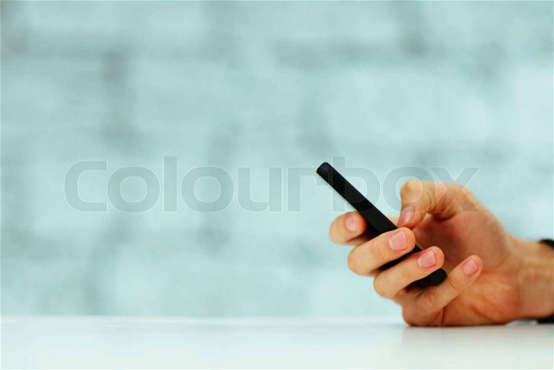 Closeup image of a male hand typing on smartphone, stock photo