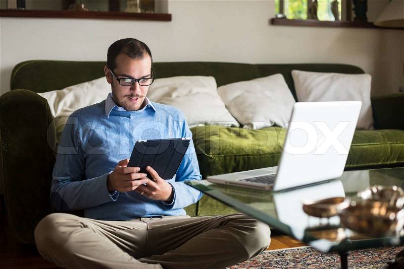 Elegant business multitasking multimedia man using devices at home, stock photo