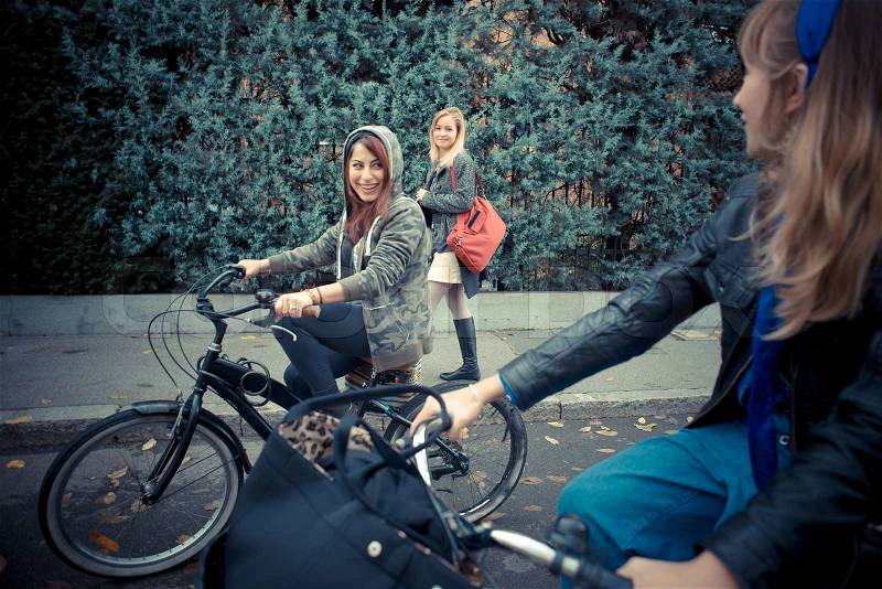 Three friends woman on bike in urban contest, stock photo
